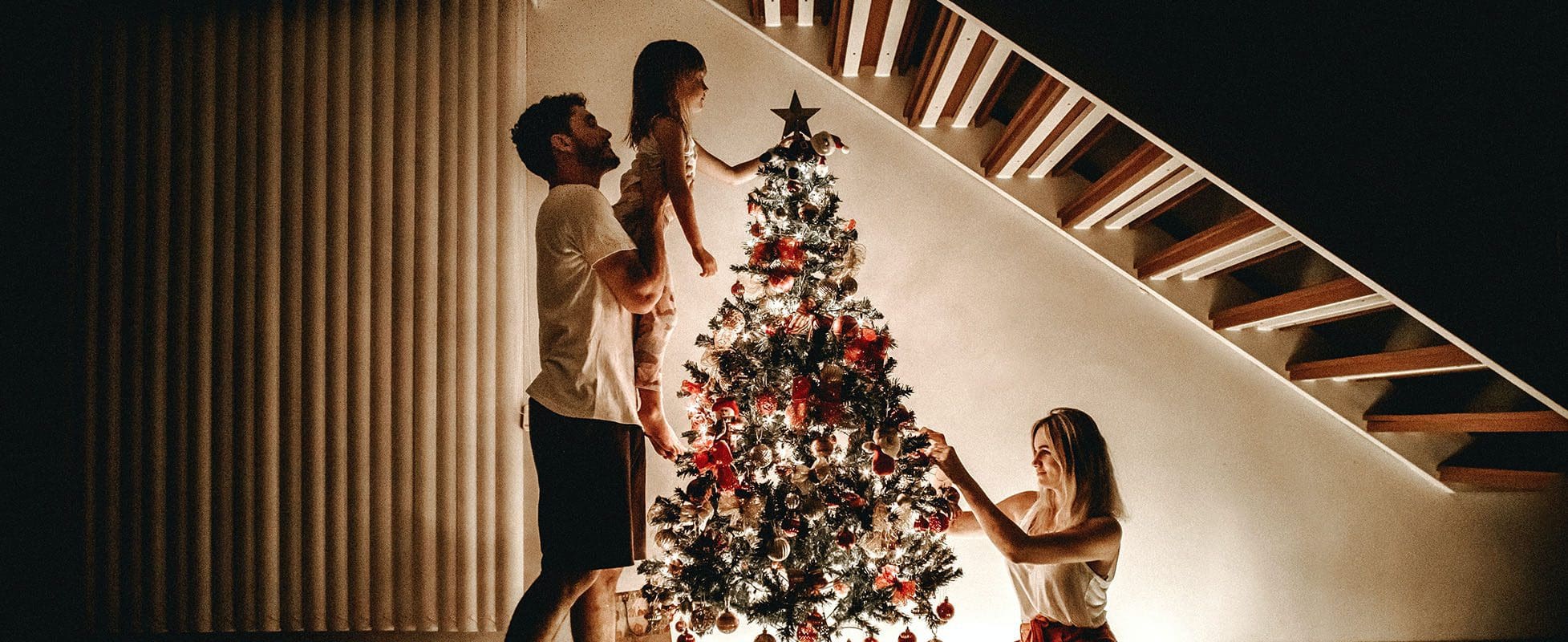 family decorating christmas tree at night family decorating christmas tree at night