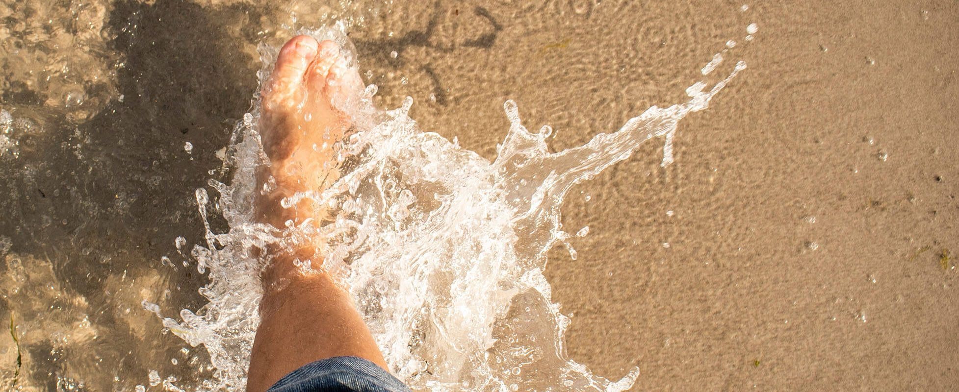 person walking in water on beach person walking in water on beach